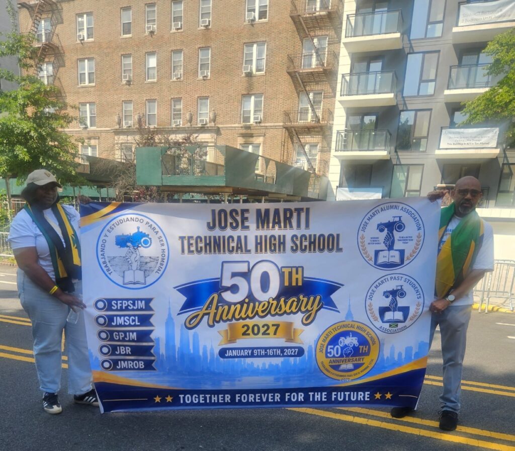 Miss Simone Gardine and Mr. Courtney Francis hold the JMTHS 50th Anniversary banner